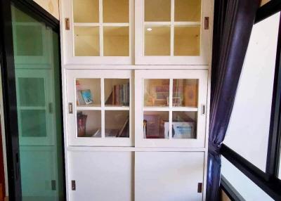 White wooden cabinet with glass doors in a room with wooden flooring and sliding door