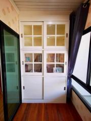 White wooden cabinet with glass doors in a room with wooden flooring and sliding door