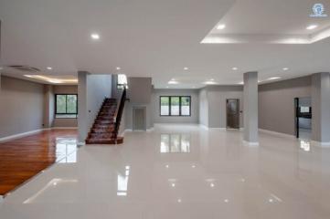 Spacious living area with glossy white floor and wooden staircase