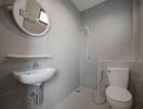 Modern gray tiled bathroom with toilet, sink, and shower