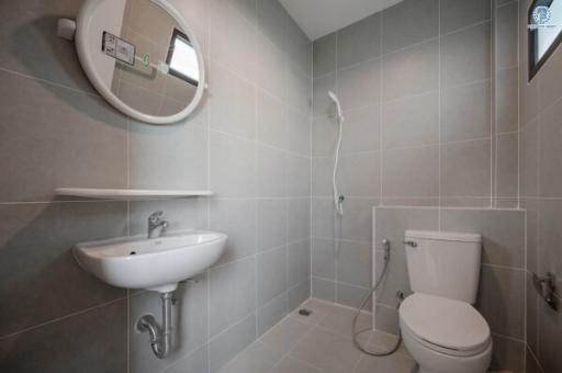 Modern gray tiled bathroom with toilet, sink, and shower