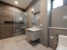 Modern bathroom with glass shower enclosure and gray tiles