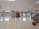 Spacious and bright entrance hall with glossy floors leading to staircase and main door