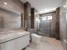 Modern bathroom with a glass shower cabin, vanity, and tiled walls