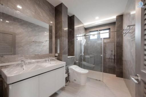 Modern bathroom with a glass shower cabin, vanity, and tiled walls