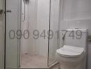 Modern white tiled bathroom with shower enclosure and toilet