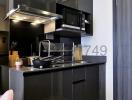 Modern compact kitchen with black cabinets and stainless steel appliances