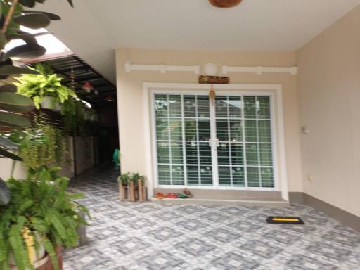 Spacious tiled patio with large windows and potted plants