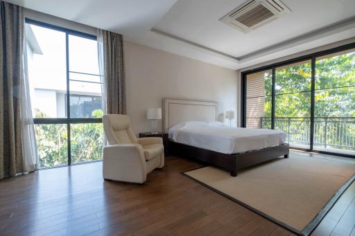 Spacious bedroom with large windows and a view of greenery