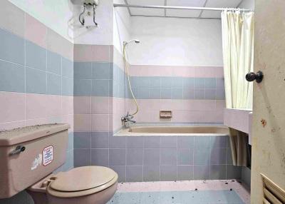 Compact bathroom with pink and blue tiles and basic fixtures