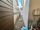 Narrow side yard of a residential property with gravel ground and fencing