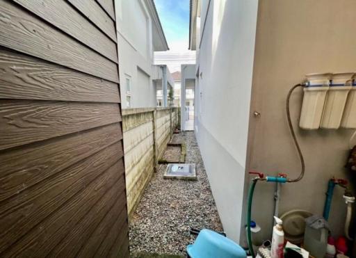 Narrow side yard of a residential property with gravel ground and fencing