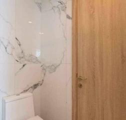 Modern bathroom with marble walls and wooden door
