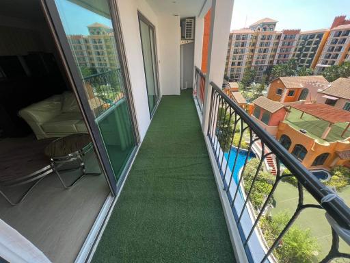 Spacious balcony with artificial grass flooring and a view of residential buildings