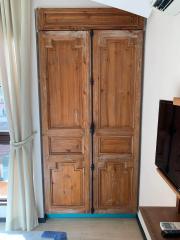 Vintage wooden double door in a living space with curtain and partial view of a television