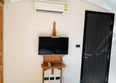 Cozy bedroom with wall-mounted television and air conditioning unit