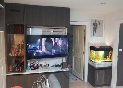 Modern living room with integrated kitchen area, large TV, and aquarium