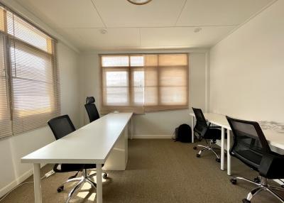 Bright and spacious office room with large windows and multiple workstations