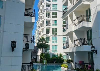 Modern residential building with balconies overlooking a communal swimming pool