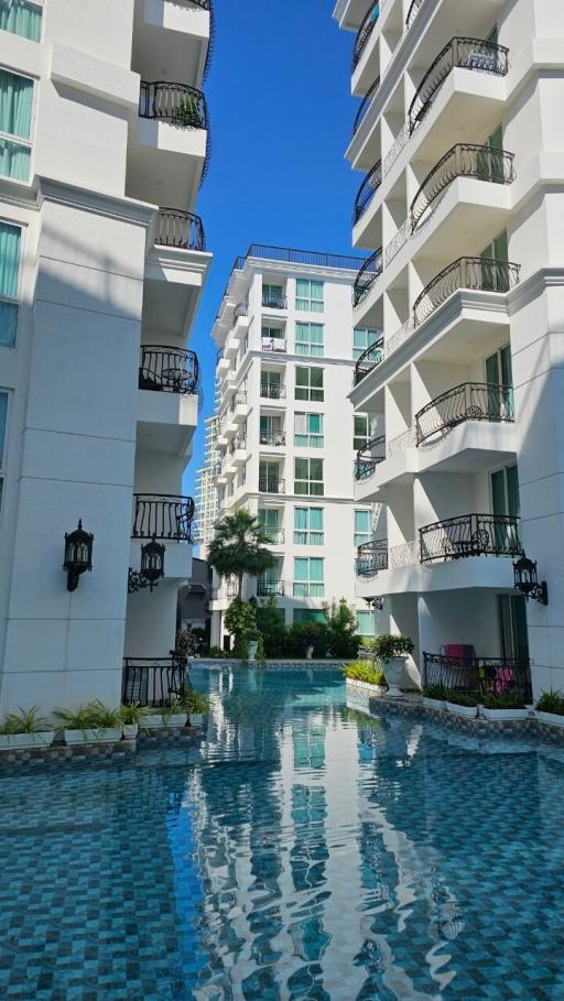 Modern residential building with balconies overlooking a communal swimming pool