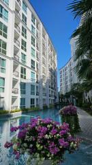 Modern residential building with balconies and a pool surrounded by flowers