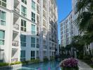 Modern residential building with balconies and a pool surrounded by flowers