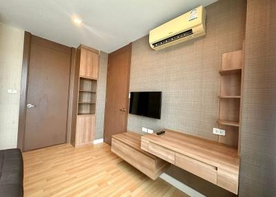 Modern living room with wooden flooring, shelving and mounted television