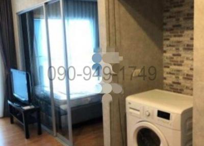 Compact bedroom with sliding glass doors, washing machine and chair