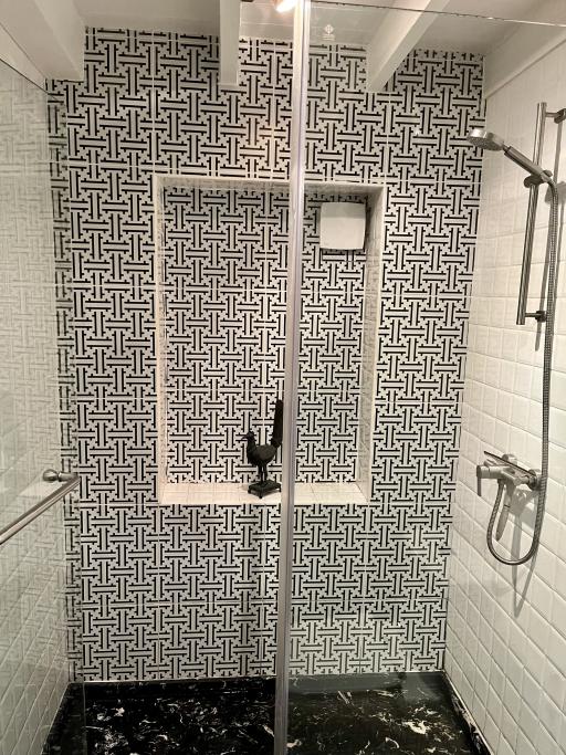 Modern bathroom with patterned tiling, glass door shower, and wall-mounted fixtures