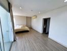 Spacious bedroom with wooden flooring and natural light