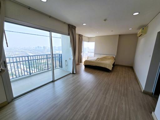 Spacious bedroom with laminate flooring and a city view through large windows