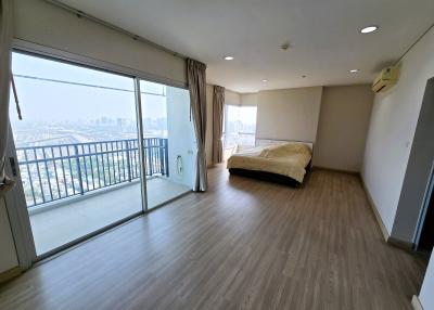 Spacious bedroom with laminate flooring and a city view through large windows