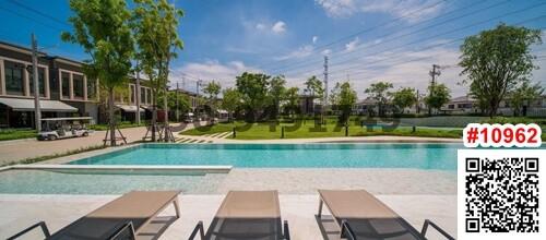 Outdoor swimming pool with loungers and townhouses in the background