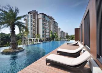 Luxurious outdoor swimming pool with lounging chairs and modern apartment building in the background