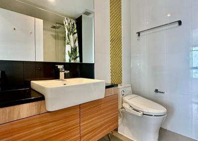Modern bathroom with wooden vanity, white fixtures, and decorative mosaic tiling