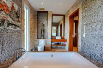 Spacious bathroom with modern finishes, featuring a large bathtub, mosaic tiles, and artwork