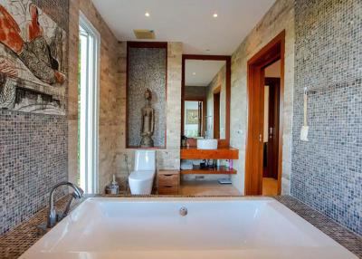Spacious bathroom with modern finishes, featuring a large bathtub, mosaic tiles, and artwork