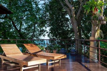 Spacious balcony with wooden deck chairs and a tranquil view of nature