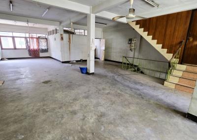 Spacious empty interior of a building with concrete floors, exposed columns, windows, and a staircase