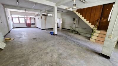 Spacious empty interior of a building with concrete floors, exposed columns, windows, and a staircase