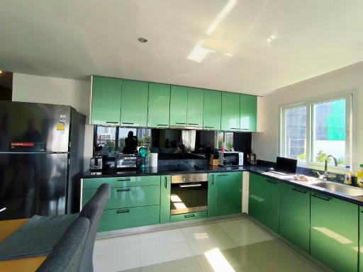 Modern kitchen with green cabinetry and stainless steel appliances