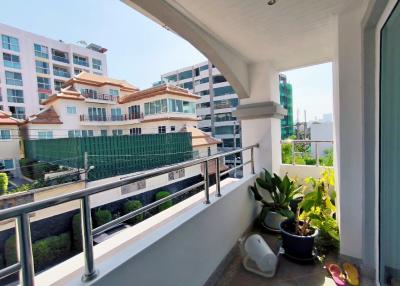 Sunny balcony with a view of neighboring buildings, plants and outdoor furniture