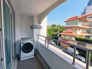 Spacious balcony with laundry machine and urban view
