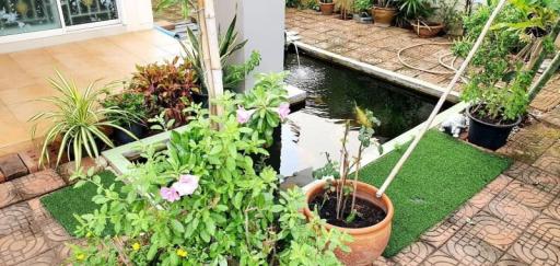 Lush garden patio with artificial grass and small pond