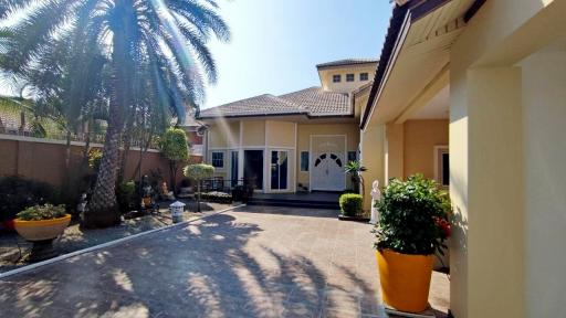 Spacious residential home exterior with paved driveway and palm trees