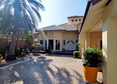 Spacious residential home exterior with paved driveway and palm trees