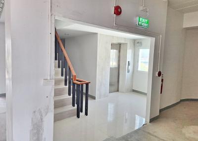 Residential building interior showing staircase and exit corridor with tiled flooring
