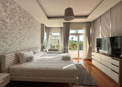 Modern bedroom with a large bed, stylish wallpaper, and access to a sunlit balcony