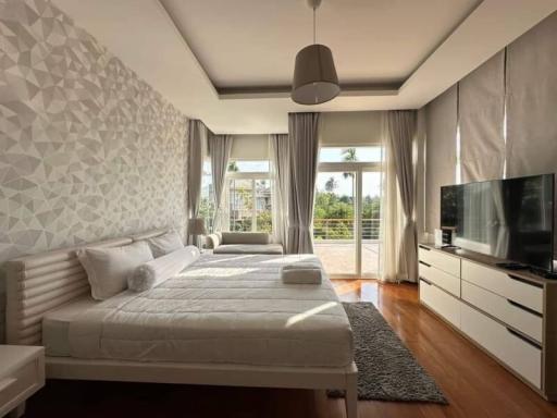 Modern bedroom with a large bed, stylish wallpaper, and access to a sunlit balcony