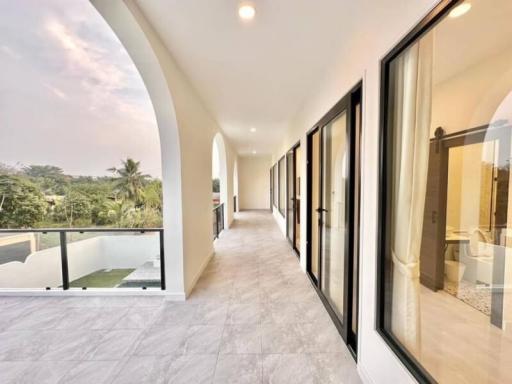 Spacious balcony with modern glass railing overlooking a green landscape